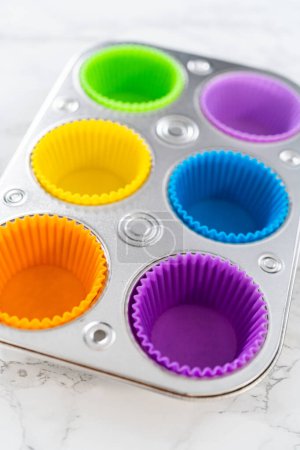 Foto de Nuevos revestimientos de cupcakes de silicona de diferentes colores en el mostrador de la cocina. - Imagen libre de derechos