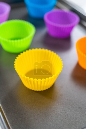 Foto de Nuevos revestimientos de cupcakes de silicona de diferentes colores en el mostrador de la cocina. - Imagen libre de derechos