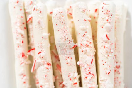 Téléchargez les photos : Pile de tiges de bretzel recouvertes de chocolat de canne à sucre maison sur une assiette de service blanche. - en image libre de droit