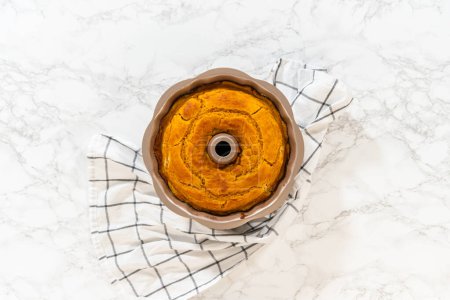 Photo for Flat lay. Cooling freshly baked pumpkin bundt cake on the kitchen counter. - Royalty Free Image