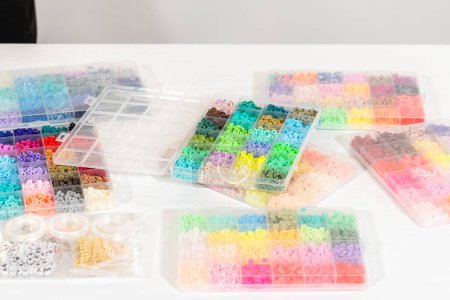 Téléchargez les photos : Assortiment de boîtes de perles d'argile soigneusement disposées sur une table blanche, en attendant un projet créatif d'artisanat pour enfants. - en image libre de droit
