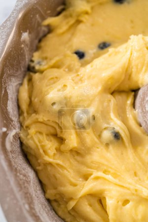 Foto de Llenado de pan de pastel de paquete de metal con mantequilla de pastel para hornear pastel de paquete de arándanos de limón. - Imagen libre de derechos