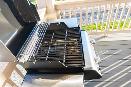 Photo for Sleek, open-lid, two-burner grill stands ready for use, conveniently positioned on the balcony of a suburban home, promising a delightful alfresco cooking experience. - Royalty Free Image