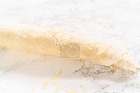 Foto de Masa de pan rellena con relleno de canela y pacanas picadas en un rollo para hornear pastelitos de canela sin levadura. - Imagen libre de derechos