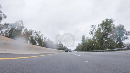 Téléchargez les photos : Au milieu d'une journée pluvieuse d'hiver, conduite sur la route 134 près de Los Angeles, Californie, capture l'atmosphère à travers des lentilles recouvertes de gouttes de pluie, ajoutant une perspective unique et lunatique au voyage. - en image libre de droit