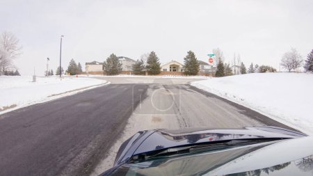 Foto de Al atravesar una carretera suburbana recién despejada después de una tormenta de invierno, uno experimenta un viaje sereno a través de un exclusivo vecindario residencial. Casas cubiertas de nieve y árboles contribuyen a un pintoresco - Imagen libre de derechos