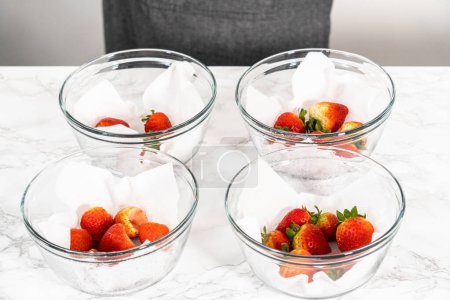 Téléchargez les photos : Les fraises fraîchement lavées et séchées sont soigneusement disposées dans un bol en verre doublé d'une serviette en papier, prêtes à être grignotées ou utilisées ultérieurement.. - en image libre de droit