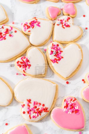 Foto de Decoración de galletas de azúcar en forma de corazón con glaseado real rosa y blanco para el Día de San Valentín. - Imagen libre de derechos