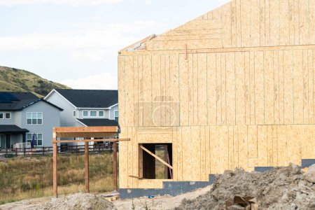 Foto de Un sitio de construcción en curso en los suburbios, con la etapa de encuadre de una casa unifamiliar. - Imagen libre de derechos