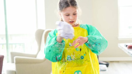 Photo for In a modern kitchen, a homeschooled girl is engrossed in creating homemade slime, a fun and educational hands-on project that enhances her creativity and problem-solving skills. - Royalty Free Image