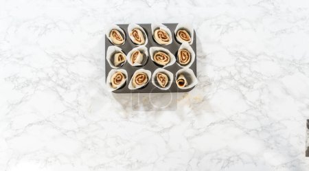 Photo for Flat lay. Filling cupcake liners with small cinnamon rolls to bake no-yeast cinnamon roll cupcakes. - Royalty Free Image