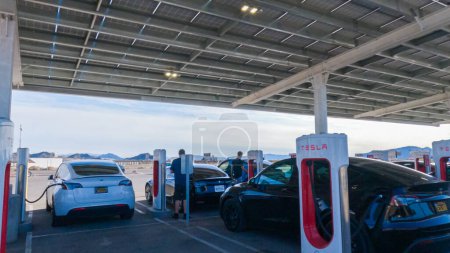 Photo for Baker, California, USA-December 3, 2022-During the day, a Tesla vehicle is seen charging at a Tesla Supercharging station, utilizing the high-speed charging infrastructure for convenient and efficient - Royalty Free Image