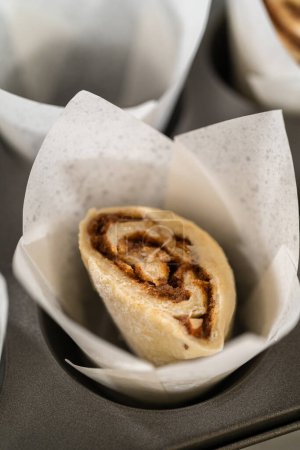 Photo for Filling cupcake liners with small cinnamon rolls to bake no-yeast cinnamon roll cupcakes. - Royalty Free Image