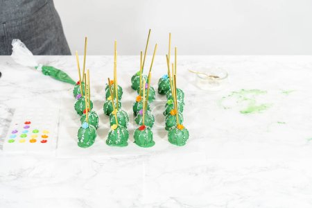 Photo for Decorating cactus cake pops with luster dust, sugar glower, and white sprinkles for the Cinco de Mayo celebration. - Royalty Free Image
