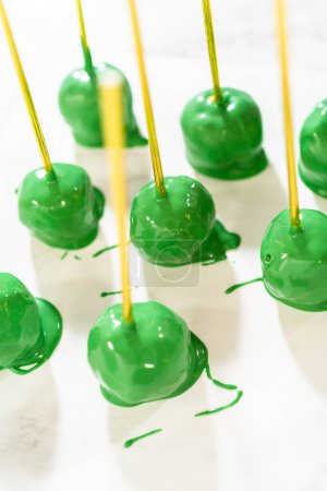 Photo for Dipping dough balls into green melted chocolate to make cactus cake pops for the Cinco de Mayo celebration. - Royalty Free Image