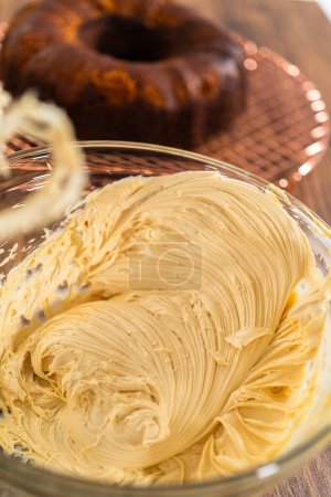 Foto de Batiendo glaseado de crema de caramelo salado para el pastel de pan de jengibre. - Imagen libre de derechos