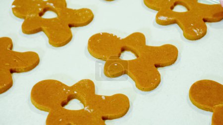 Photo for Freshly cut-out gingerbread cookies rest on a baking sheet, lined with parchment paper, awaiting a cool and refreshing chill in the fridge before their delicious transformation in the oven. - Royalty Free Image