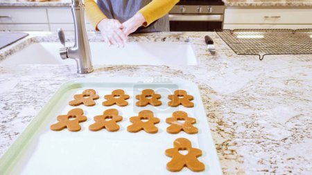 Photo for Freshly cut-out gingerbread cookies rest on a baking sheet, lined with parchment paper, awaiting a cool and refreshing chill in the fridge before their delicious transformation in the oven. - Royalty Free Image