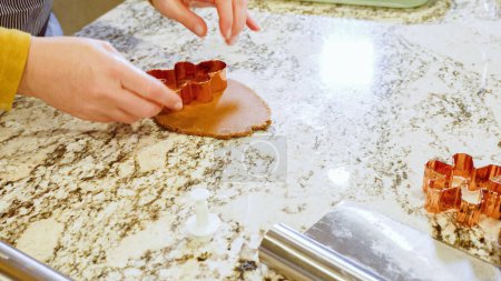 Usando varios cortadores de galletas festivas, estaban cortando encantadoras galletas de jengibre de la masa enrollada en el elegante mostrador de mármol, trayendo alegría navideña a la cocina moderna.