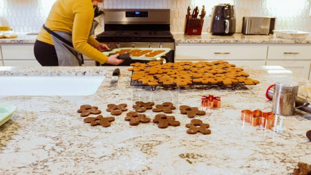 Foto de Después de hornear a la perfección, estas deliciosas galletas de jengibre se están enfriando con gracia en un estante de alambre, llenando la cocina moderna con un aroma cálido y acogedor. - Imagen libre de derechos