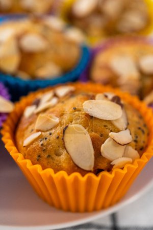 Photo for Freshly baked lemon poppy seed muffins garnished with almond slivers on the kitchen counter. - Royalty Free Image