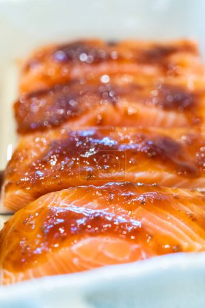 Photo for Baking pieces of fresh salmon with teriyaki sauce in an oven-safe ceramic dish. - Royalty Free Image