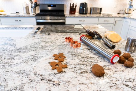 Téléchargez les photos : Dans une cuisine blanche contemporaine, la pâte à biscuits au pain d'épice est habilement déroulée, préparant le terrain pour une délicieuse gâterie de vacances. - en image libre de droit