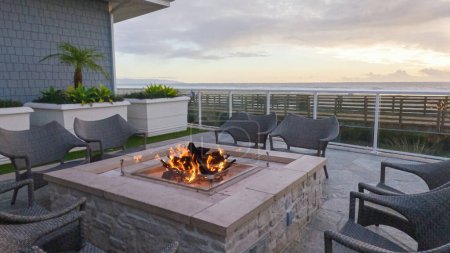Photo for As the sun sets over Pismo Beach, the outdoor fireplace at a local hotel flickers to life, casting a warm and inviting glow. Guests gather around to enjoy the crackling fire and the stunning backdrop - Royalty Free Image