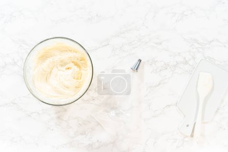 Photo for Flat lay. Transferring the homemade cream cheese frosting into a piping bag, ready to create beautiful and delicious decorations. - Royalty Free Image