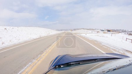 Die Navigation auf einer Frontstraße nach dem Wintersturm bietet eine ruhige Fahrt. Die schneebedeckte Landschaft in der Umgebung trägt zu einer friedlichen und malerischen Umgebung bei, die das Autofahren fördert.