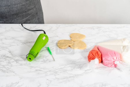 Foto de Gelatina real casera en bolsas de tuberías listas para decorar galletas de azúcar en el mostrador de la cocina. - Imagen libre de derechos