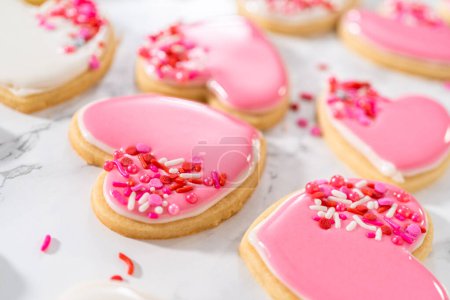 Téléchargez les photos : Décoration de biscuits au sucre en forme de cœur avec glaçage royal rose et blanc pour la Saint-Valentin. - en image libre de droit