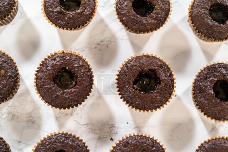 Foto de Cada cupcake de chocolate recibe un generoso relleno de delicioso caramelo, añadiendo una capa extra de sabor e indulgencia. - Imagen libre de derechos