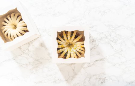 Téléchargez les photos : Pose plate. Les gâteaux bundt fraîchement cuits sont soigneusement nichés dans des boîtes en papier blanc, les préparant pour un transport sûr tout en conservant leur apparence délectable. - en image libre de droit