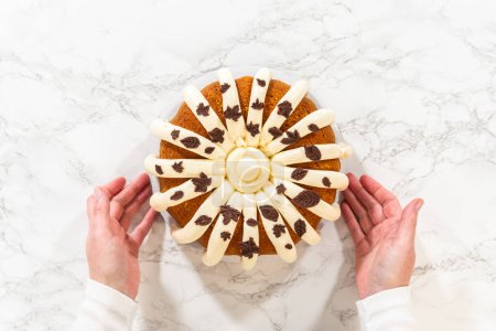 Foto de Acostado. Helar el pastel de calabaza con glaseado de queso crema y decorarlo con hojas de chocolate. - Imagen libre de derechos