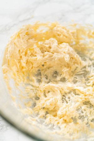 Téléchargez les photos : Mélanger les ingrédients dans un bol à mélanger en verre pour faire le glaçage au fromage à la crème pour les cupcakes sans levure à la cannelle. - en image libre de droit