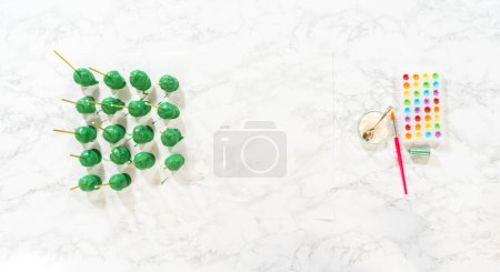 Photo for Flat lay. Dipping dough balls into green melted chocolate to make cactus cake pops for the Cinco de Mayo celebration. - Royalty Free Image