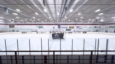 Téléchargez les photos : Denver, Colorado, États-Unis-17 février 2024 - Une patinoire se déplace sur la surface d'une patinoire de hockey vide, entourée de bannières et de sièges, préparant la glace pour les athlètes et les patineurs. - en image libre de droit