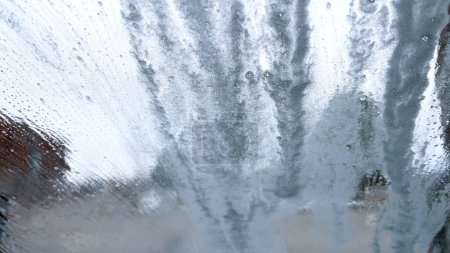 Téléchargez les photos : Vue savonneuse du pare-brise de l'intérieur d'une voiture pendant un cycle de lavage automatique, avec la mousse obscurcissant l'extérieur. - en image libre de droit