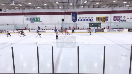 Photo for Denver, Colorado, USA-February 17, 2024-Young athletes in the midst of a lively hockey game, with players chasing the puck across the ice rink bordered by spectators. - Royalty Free Image