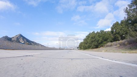 Téléchargez les photos : Par une belle journée d'hiver, une voiture parcourt l'emblématique Highway 101 près de San Luis Obispo, en Californie. Le paysage environnant est brunâtre et tamisé, avec des collines ondulantes et des zones côtières - en image libre de droit