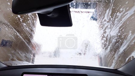 Photo for Soapy windshield view from inside a car during an automatic wash cycle, with the foam obscuring the outside. - Royalty Free Image