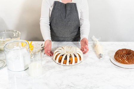 Photo for The final stage of this delightful baking journey involves artistically piping the silky cream cheese buttercream frosting atop the cooled bundt cakes, creating an irresistible treat. - Royalty Free Image
