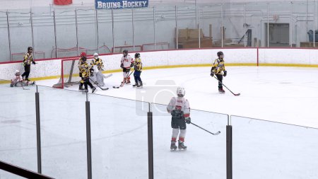 Téléchargez les photos : Denver, Colorado, États-Unis-17 février 2024-Les jeunes athlètes au milieu d'un match de hockey animé, avec des joueurs pourchassant la rondelle à travers la patinoire bordée de spectateurs. - en image libre de droit