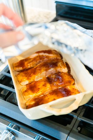 Téléchargez les photos : Cuisson de morceaux de saumon frais avec sauce teriyaki dans un plat en céramique allant au four. - en image libre de droit
