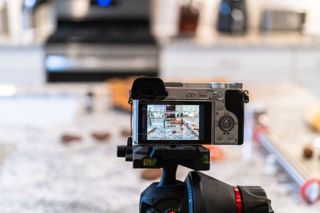 Téléchargez les photos : Un appareil photo reflex numérique, installé dans une cuisine élégante et moderne, capture la réalisation d'une recette vidéo pour vlogging. - en image libre de droit