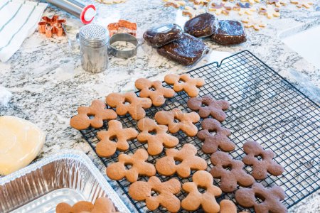 Photo for Freshly baked gingerbread cookies find their place on a cooling wire rack in a modern white kitchen, filling the air with festive aromas. - Royalty Free Image