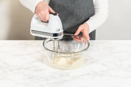 Foto de Mezclar los ingredientes en un tazón de vidrio para hacer el glaseado de queso crema para cupcakes de canela sin levadura. - Imagen libre de derechos