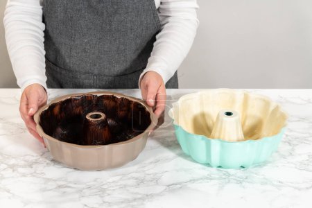 Preparing the bundt cake pan for baking, a mixture of melted vegetable shortening and cocoa powder is skillfully applied to ensure easy release and a beautifully baked bundt cake.