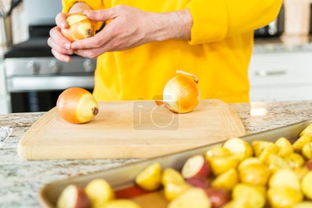 Photo for On a wooden cutting board, a fresh yellow onion is being neatly sliced. These uniform pieces are destined for the grill, where they will transform under the flame, offering a caramelized sweetness to - Royalty Free Image